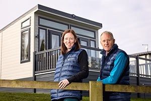 Lady and Gentleman outside of a Willerby Caravan Model with new sustainability stand cutting energy bills